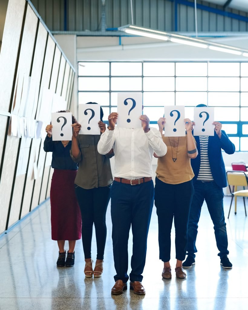 Shot of a group of businesspeople holding up placards with question marks on it.